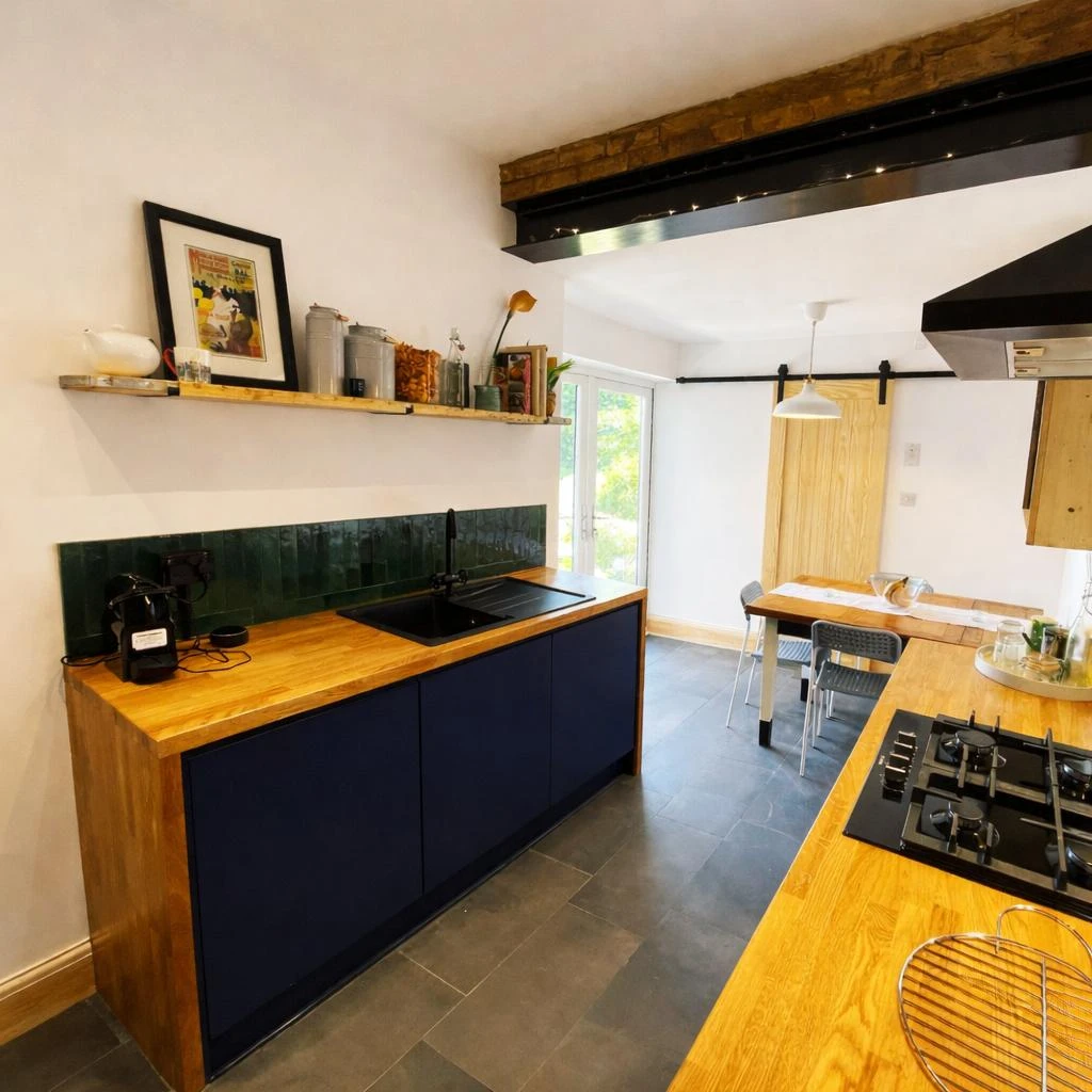 Modern kitchen featuring wooden cabinets, a black sink, green tile backsplash, and a dining area with natural light.