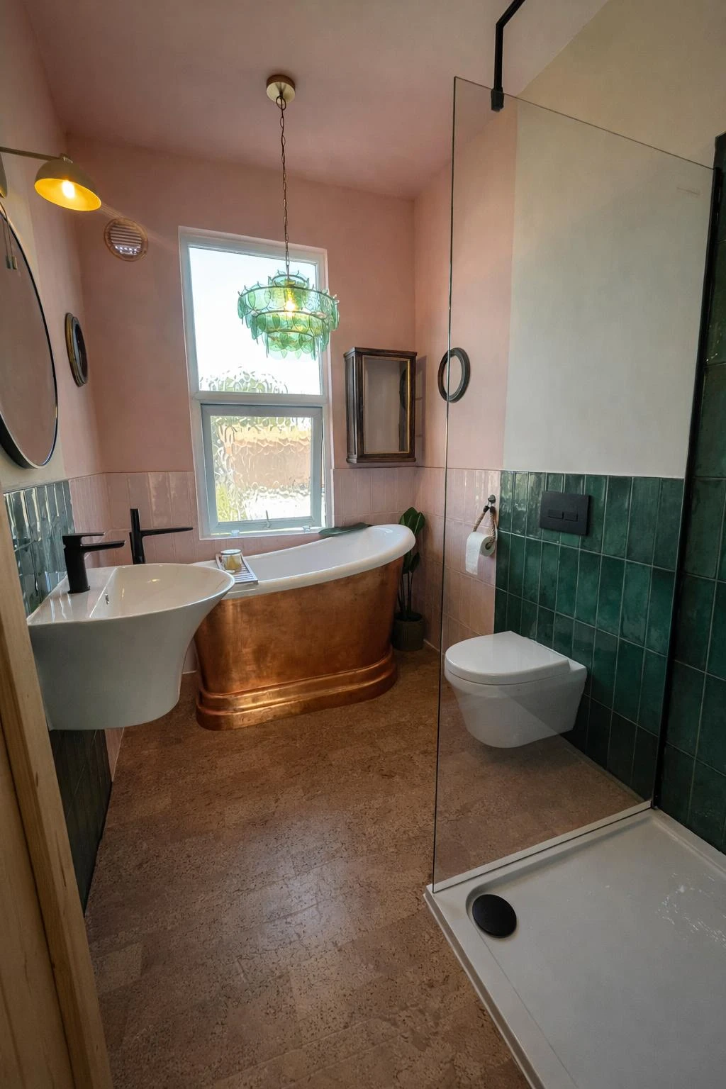 Elegant bathroom featuring a copper bathtub, green tile accents, modern sink, and a glass shower enclosure with natural light.