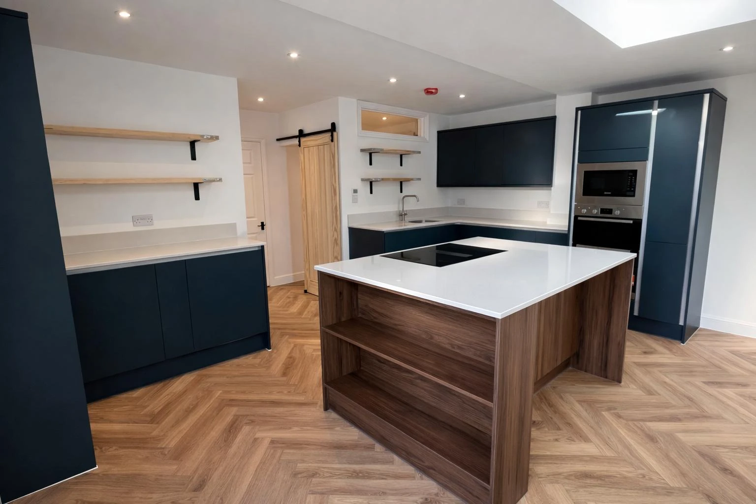 Modern kitchen featuring navy cabinetry, wood accents, and a large island with a white countertop and stovetop.